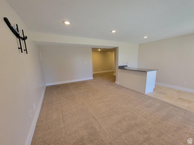 empty room featuring recessed lighting, light carpet, baseboards, and a textured ceiling
