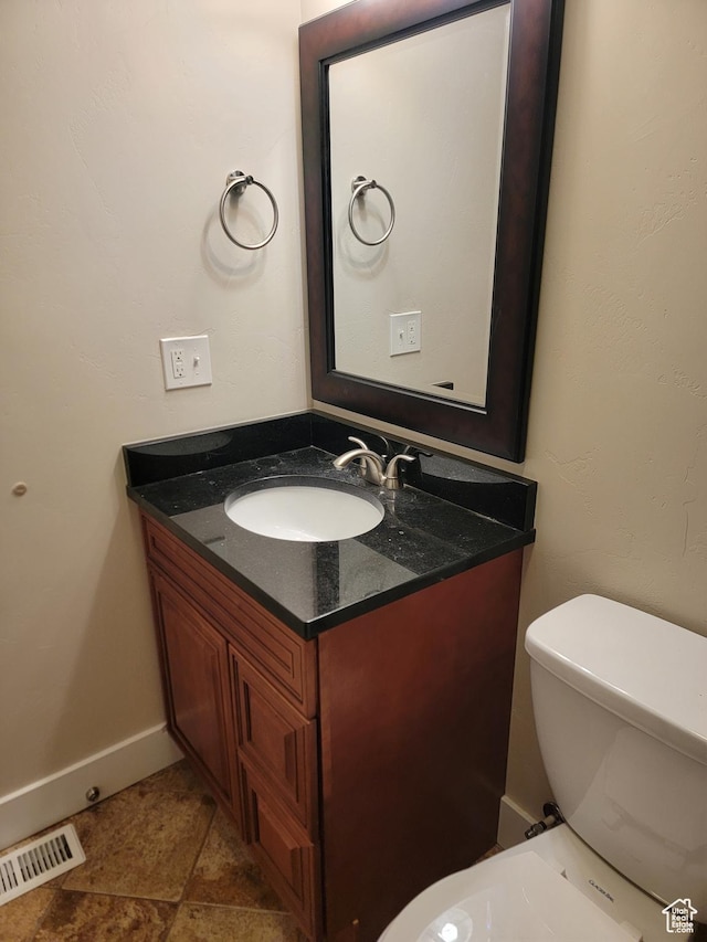 half bath featuring vanity and toilet