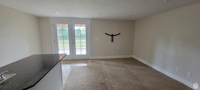 entryway with french doors, a textured ceiling, and baseboards