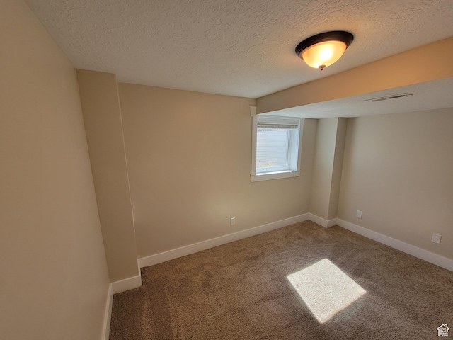 carpeted empty room featuring a textured ceiling and baseboards
