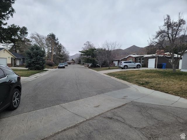 view of asphalt street with a residential view and curbs