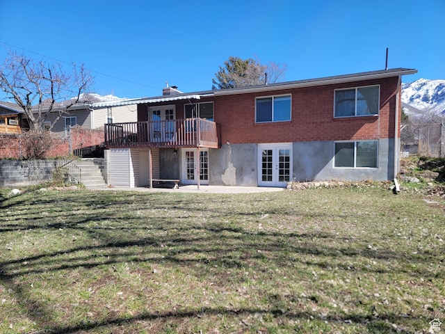 back of house with french doors, stairway, a lawn, a deck with mountain view, and a patio