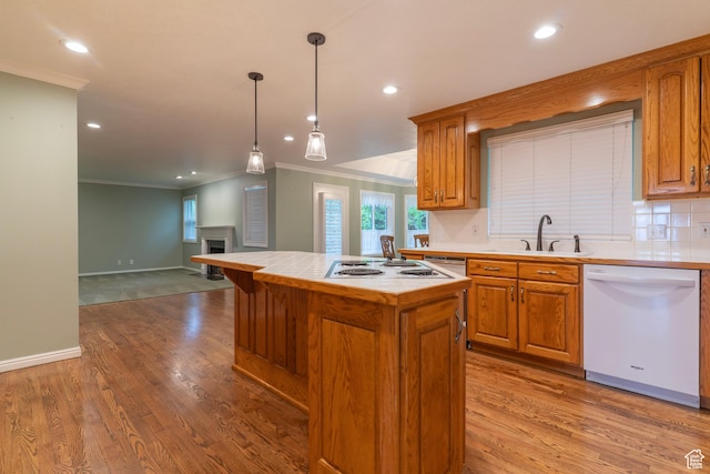 kitchen featuring white appliances, ornamental molding, a sink, wood finished floors, and tasteful backsplash