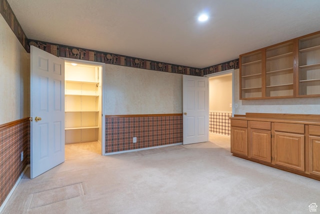 kitchen featuring a wainscoted wall, light carpet, open shelves, and wallpapered walls