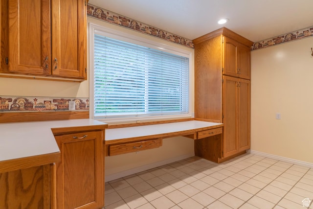 kitchen featuring light countertops, brown cabinetry, light tile patterned flooring, and baseboards