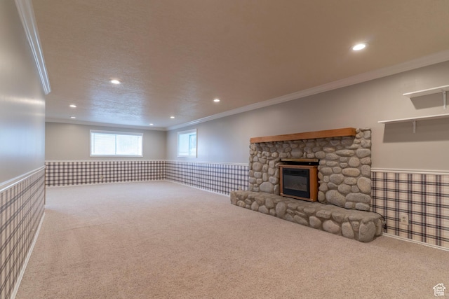 unfurnished living room with ornamental molding, recessed lighting, a wainscoted wall, a stone fireplace, and carpet flooring