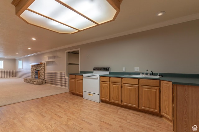 kitchen with white electric range oven, a sink, ornamental molding, light wood-style floors, and wainscoting