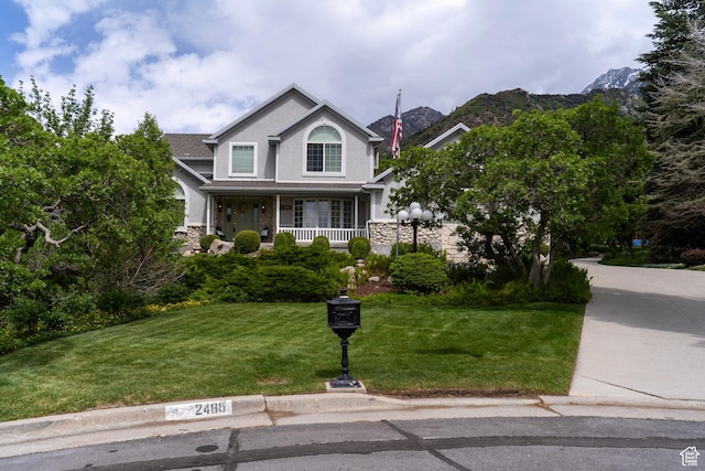 view of front of home with a front yard, a porch, stone siding, and stucco siding