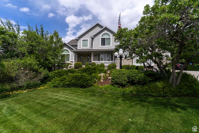 view of front of home with a front lawn, covered porch, and stucco siding