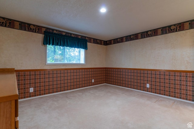 carpeted spare room featuring a wainscoted wall and wallpapered walls