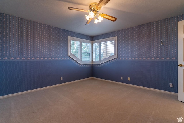 empty room with ceiling fan, wallpapered walls, carpet floors, and baseboards