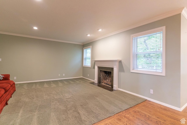 unfurnished living room featuring a fireplace with flush hearth, ornamental molding, baseboards, recessed lighting, and wood finished floors