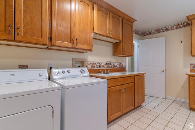 clothes washing area with washing machine and dryer, cabinet space, light tile patterned floors, and baseboards