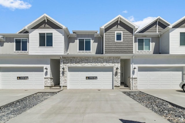 651 W 575 N, Smithfield, UT 84335 - view of front of house with board and batten siding, an attached garage, stone siding, and driveway