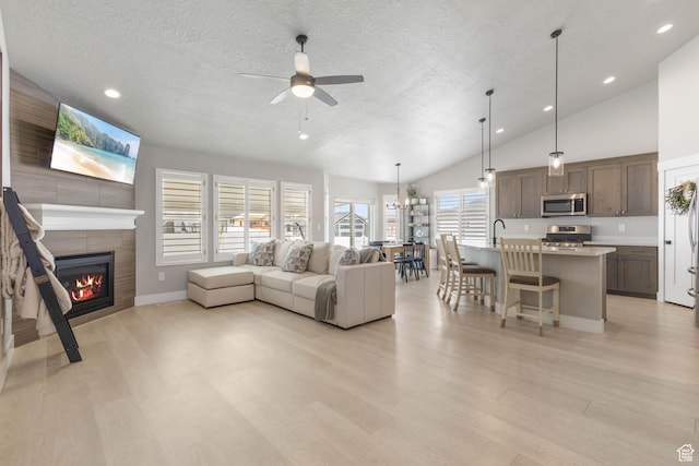 541 W 1960 N, Tooele, UT 84074 - living area with a textured ceiling, ceiling fan, a tile fireplace, light wood-style flooring, and lofted ceiling