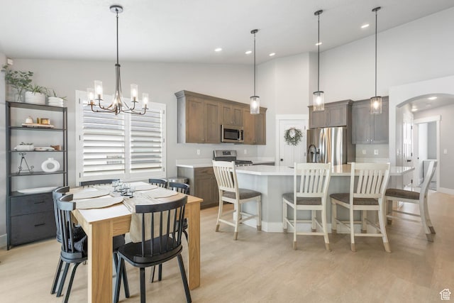 541 W 1960 N, Tooele, UT 84074 - dining area with arched walkways, light wood-type flooring, a chandelier, high vaulted ceiling, and baseboards