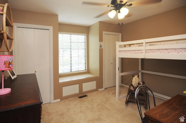 bedroom featuring light carpet, ceiling fan, and two closets