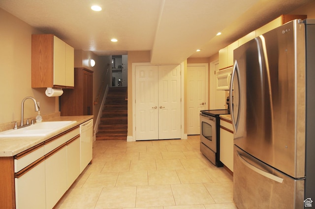 kitchen featuring stainless steel appliances, a sink, recessed lighting, white cabinetry, and light tile patterned floors