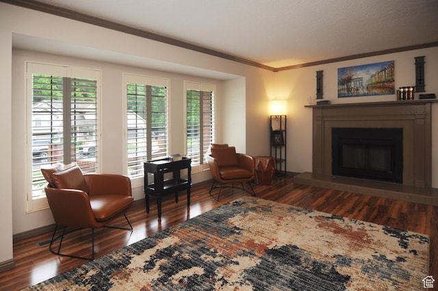 living area with ornamental molding, wood finished floors, plenty of natural light, and a fireplace with raised hearth