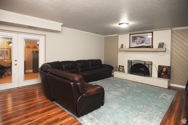 living area featuring french doors, wood finished floors, crown molding, a brick fireplace, and a textured ceiling