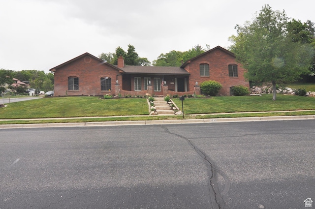 view of front of home with a chimney, a front yard, and brick siding