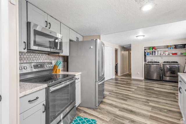 396 S 100 E, Tooele, UT 84074 - kitchen featuring stainless steel appliances, washing machine and dryer, light countertops, light wood finished floors, and a textured ceiling