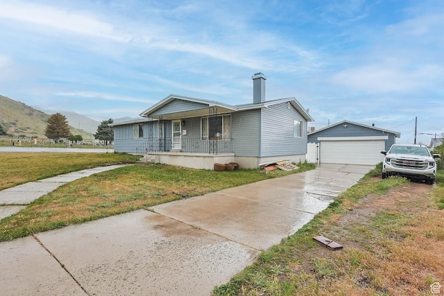 396 S 100 E, Tooele, UT 84074 - view of front of house featuring a porch, a front yard, an outdoor structure, a mountain view, and a detached garage