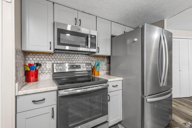 396 S 100 E, Tooele, UT 84074 - kitchen with stainless steel appliances, tasteful backsplash, wood finished floors, and a textured ceiling