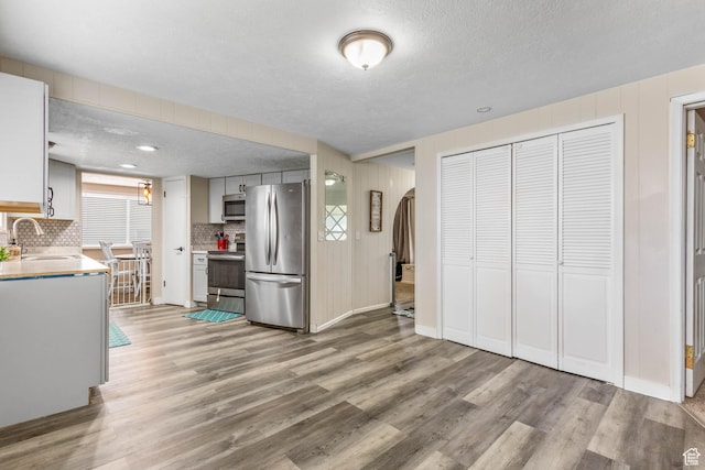 396 S 100 E, Tooele, UT 84074 - kitchen with stainless steel appliances, a sink, light wood-style flooring, decorative backsplash, and light countertops