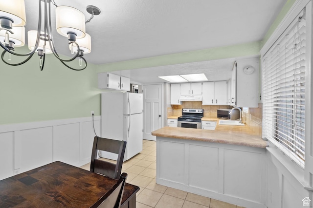 kitchen featuring freestanding refrigerator, stainless steel range with electric cooktop, under cabinet range hood, light countertops, and a sink