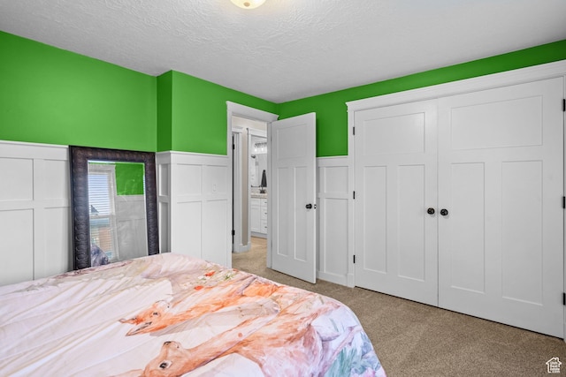 bedroom featuring light colored carpet, a textured ceiling, and a closet