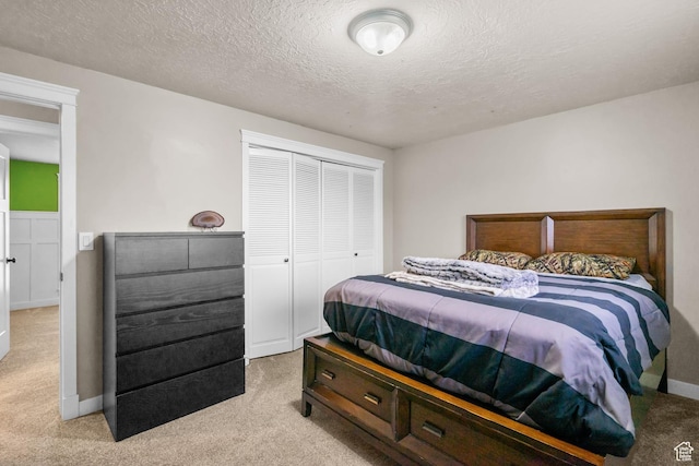 bedroom with light colored carpet, a closet, a textured ceiling, and baseboards