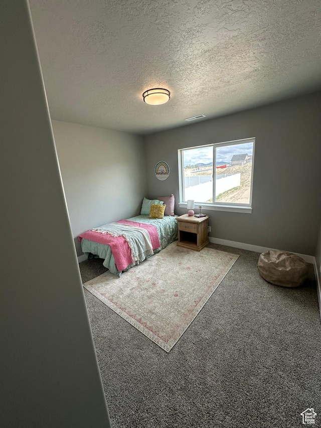 bedroom with a textured ceiling, carpet floors, and baseboards