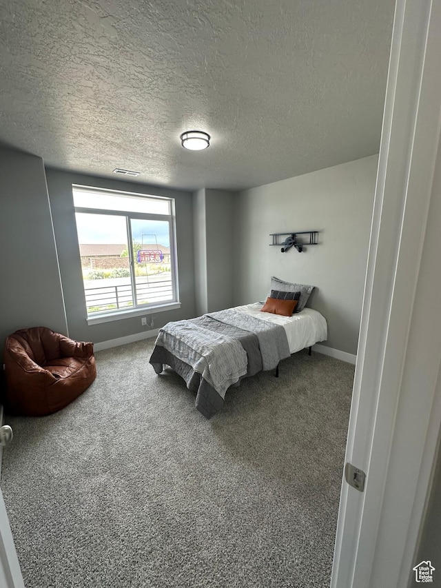 carpeted bedroom with a textured ceiling and baseboards
