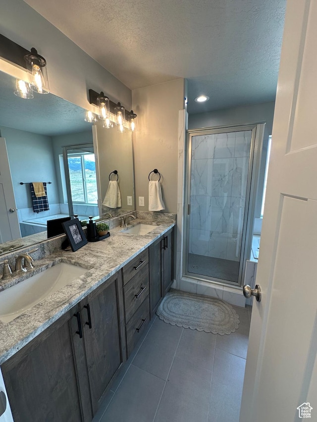 bathroom with a textured ceiling, a shower stall, double vanity, and tile patterned floors
