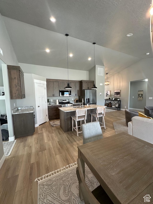 dining space with vaulted ceiling, light wood-type flooring, recessed lighting, a textured ceiling, and baseboards