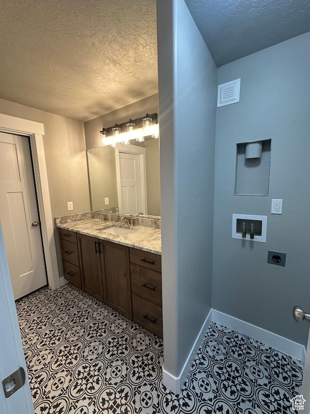 bathroom featuring a textured ceiling, baseboards, vanity, and tile patterned floors