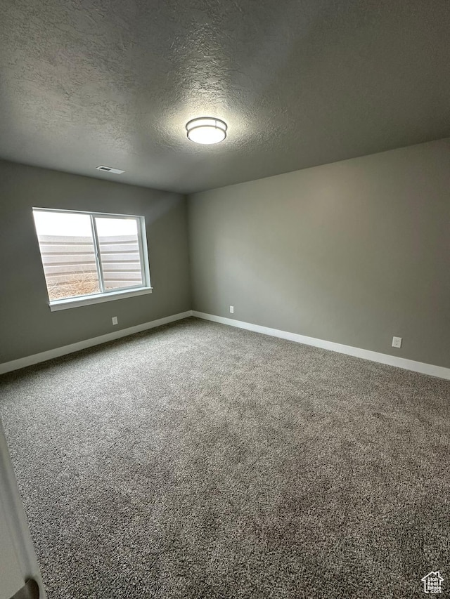 carpeted empty room with baseboards and a textured ceiling