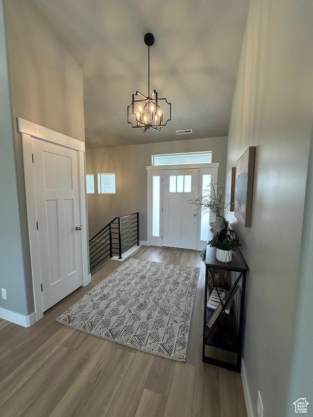 entrance foyer with a chandelier, baseboards, and wood finished floors
