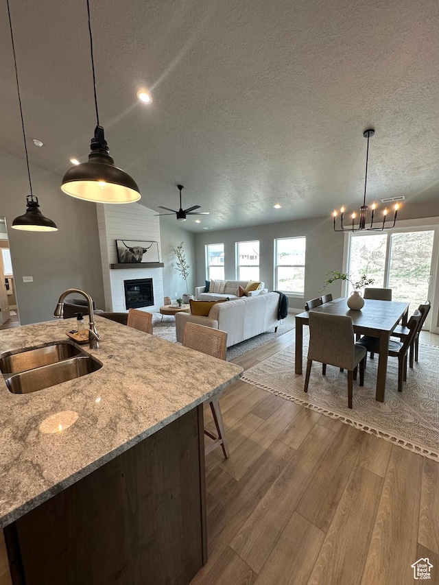 kitchen featuring a sink, a textured ceiling, a chandelier, recessed lighting, and a large fireplace