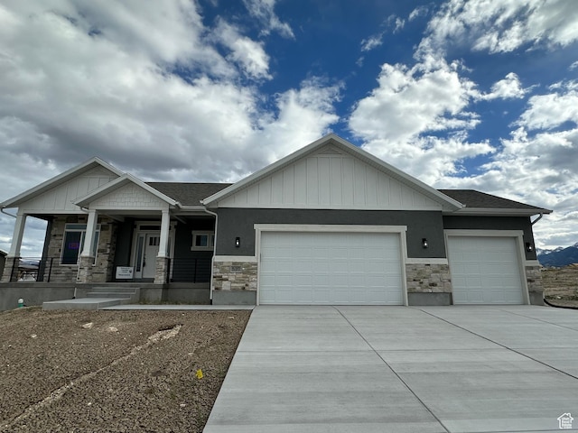 craftsman inspired home featuring stone siding, a garage, driveway, and a porch