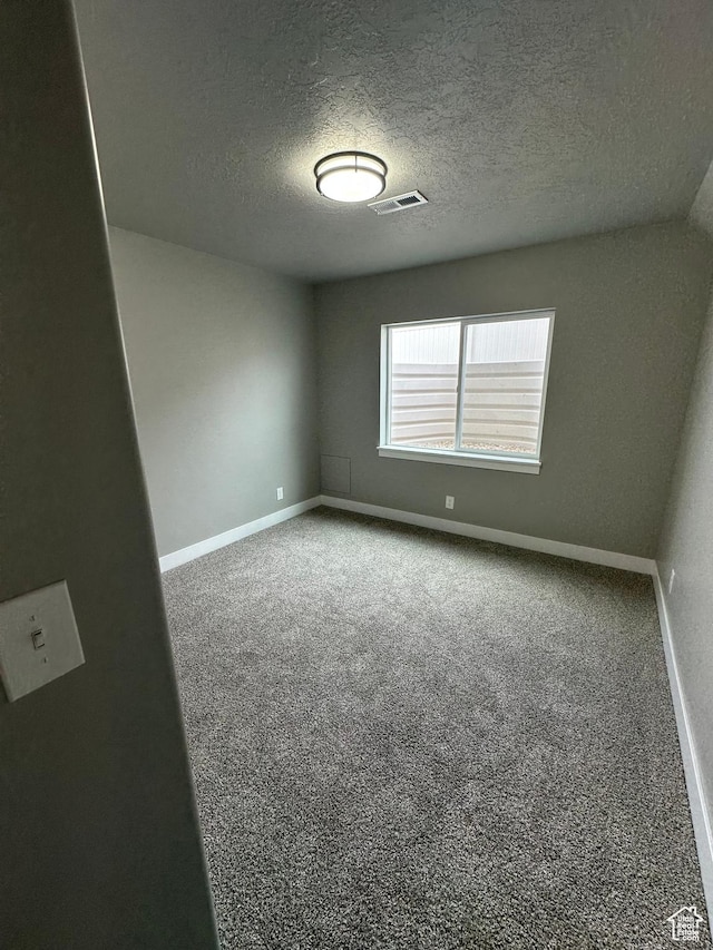 carpeted empty room with baseboards and a textured ceiling