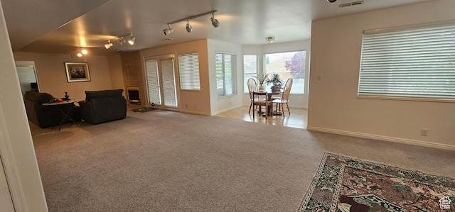 carpeted living room featuring track lighting, baseboards, and a fireplace