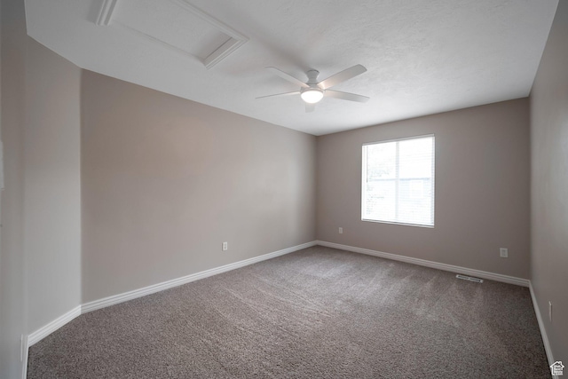 empty room with carpet floors, attic access, and baseboards