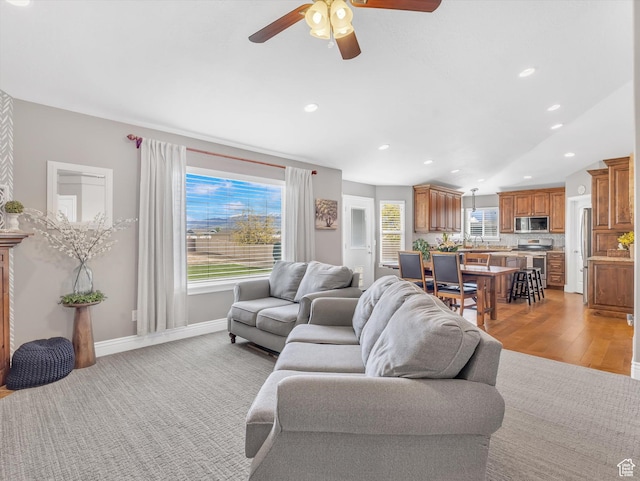living room featuring a ceiling fan, recessed lighting, baseboards, and light wood-type flooring