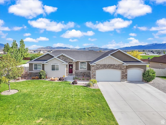 ranch-style house with stone siding, a mountain view, a garage, and concrete driveway