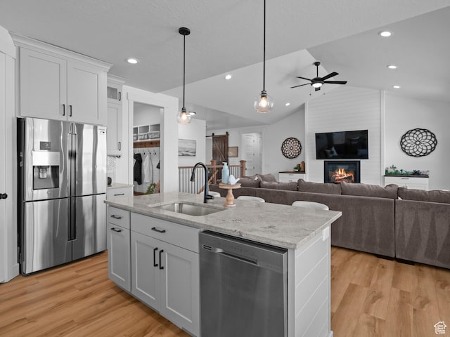 kitchen with stainless steel appliances, a sink, open floor plan, a ceiling fan, and lofted ceiling