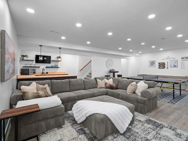 living area with recessed lighting, wood finished floors, stairs, and bar with sink