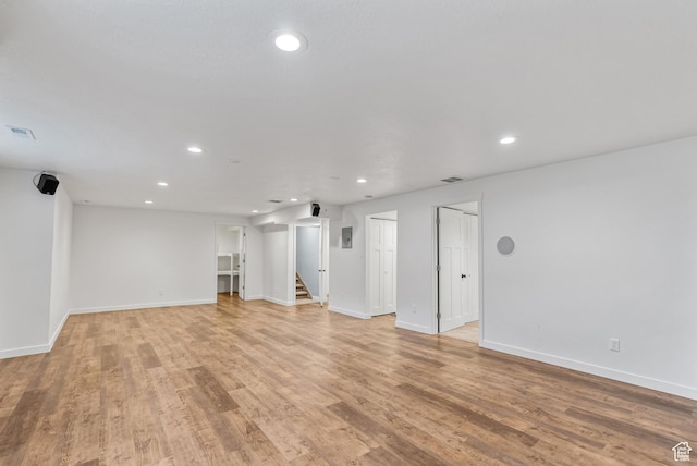 unfurnished living room featuring recessed lighting, stairs, light wood-type flooring, and baseboards