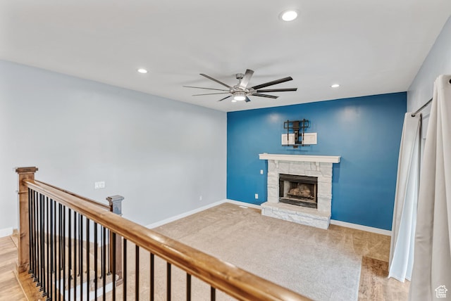 living area with a ceiling fan, a stone fireplace, baseboards, and recessed lighting